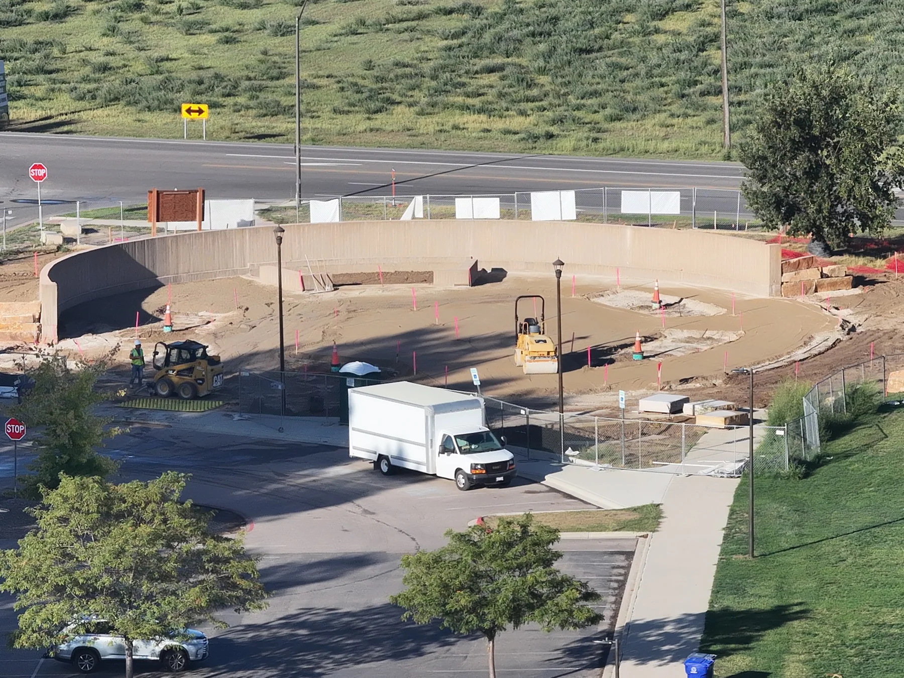 September 22 aerial view of a curved wall and adjoining construction area, with access roads and surrounding site context